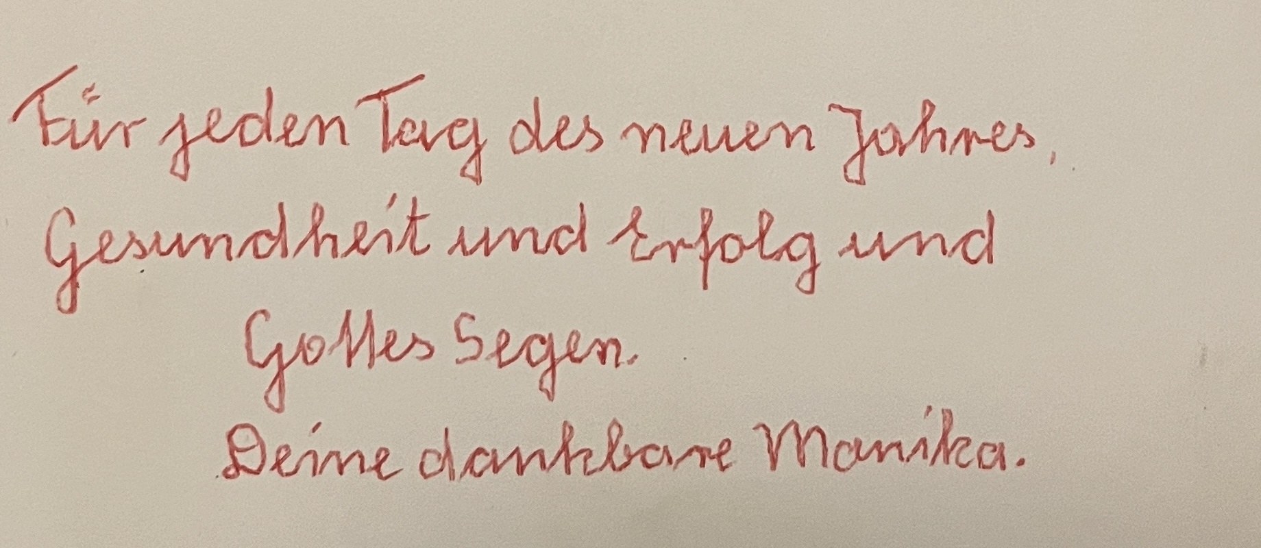 Der eigenhändige Neujahrsgruß in roter Schrift am Fuß der Karte